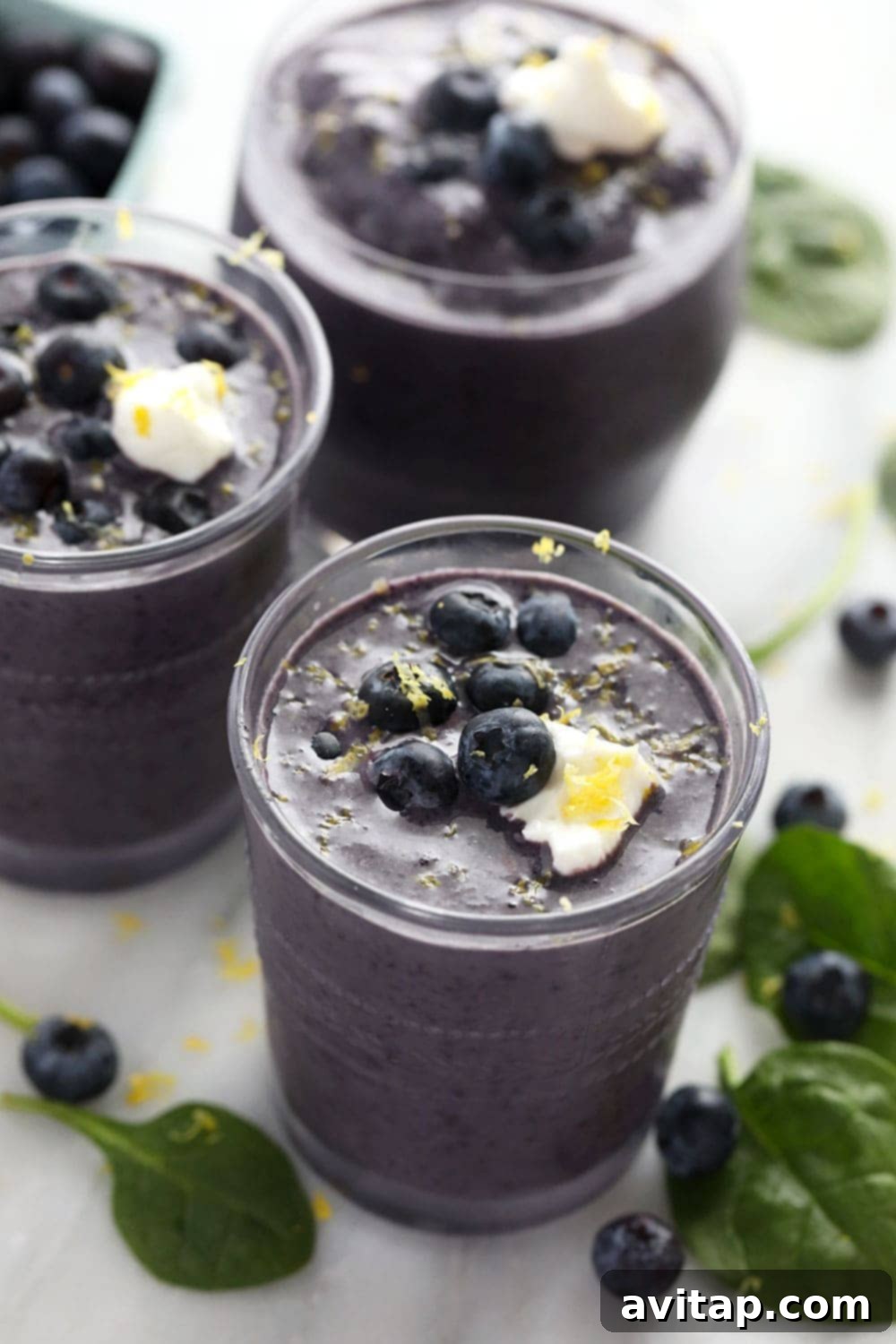 Vibrant blueberry flaxseed superfood smoothie in a clear glass with fresh blueberries and a straw.
