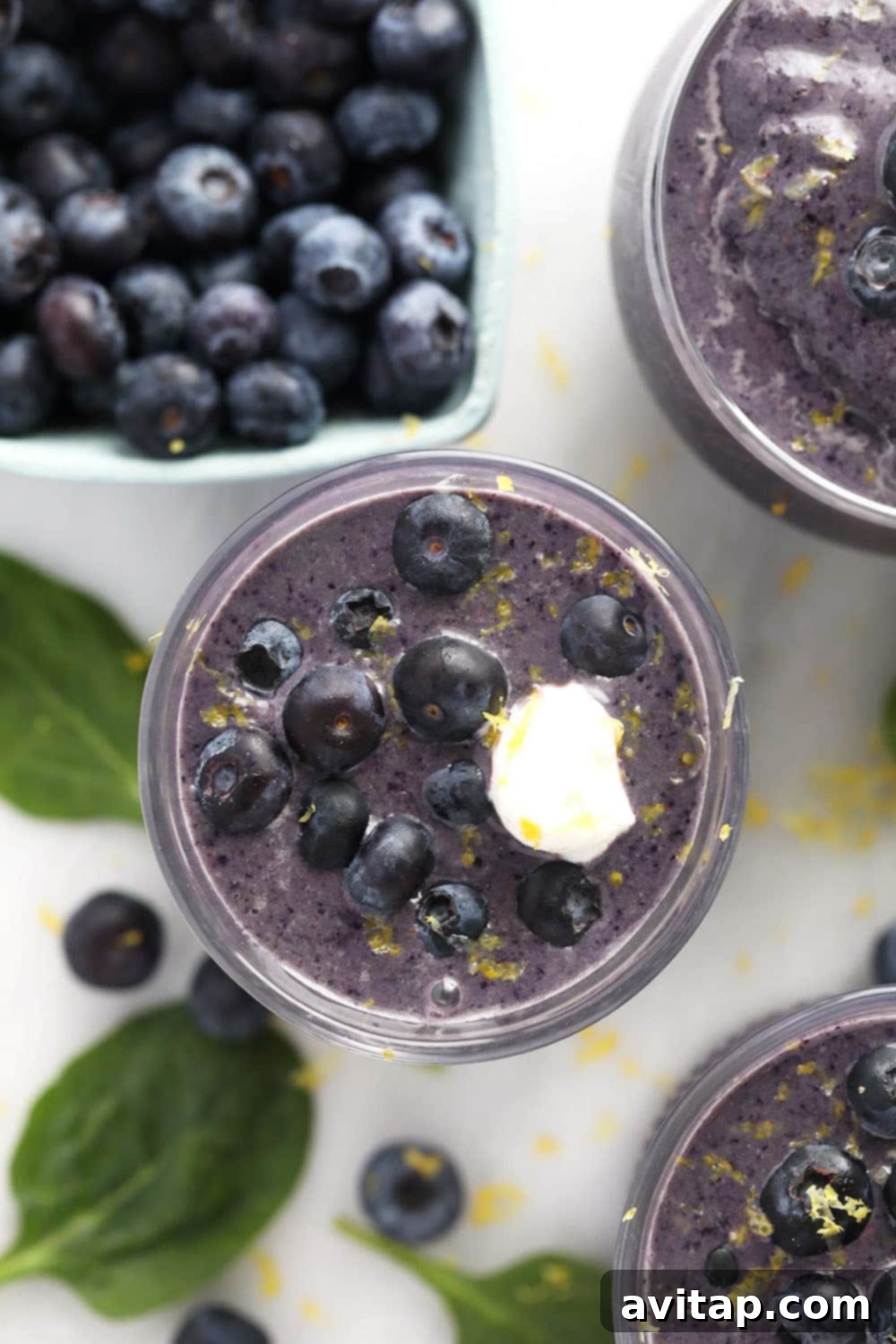 Two glasses of Blueberry Flax Superfood Smoothie garnished with fresh blueberries and mint leaves.