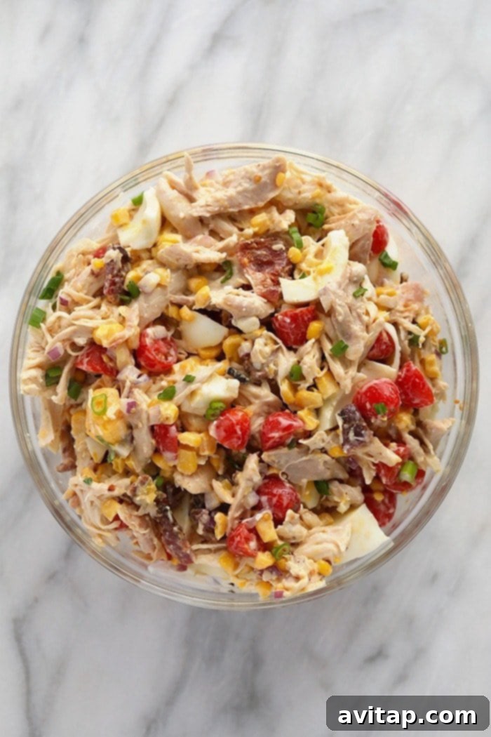 A generous serving of Rotisserie Chicken Cobb Salad in a bowl, garnished and ready to be enjoyed.
