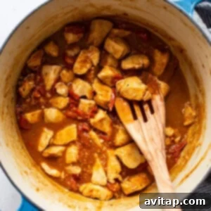 Chicken simmering in a rich balsamic and white wine sauce in a large pot.