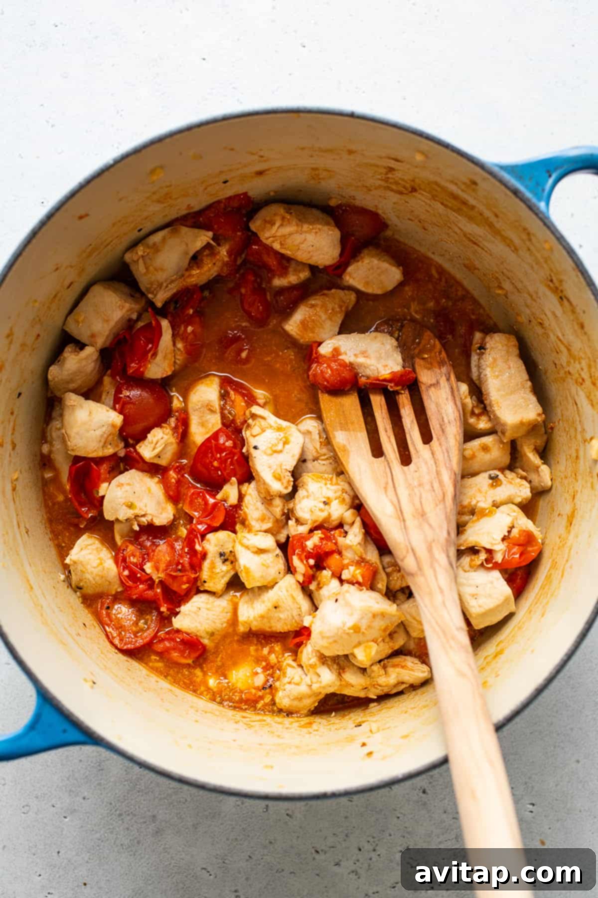 Cooking succulent chicken breast and vibrant cherry tomatoes in a large pot for Caprese pasta.