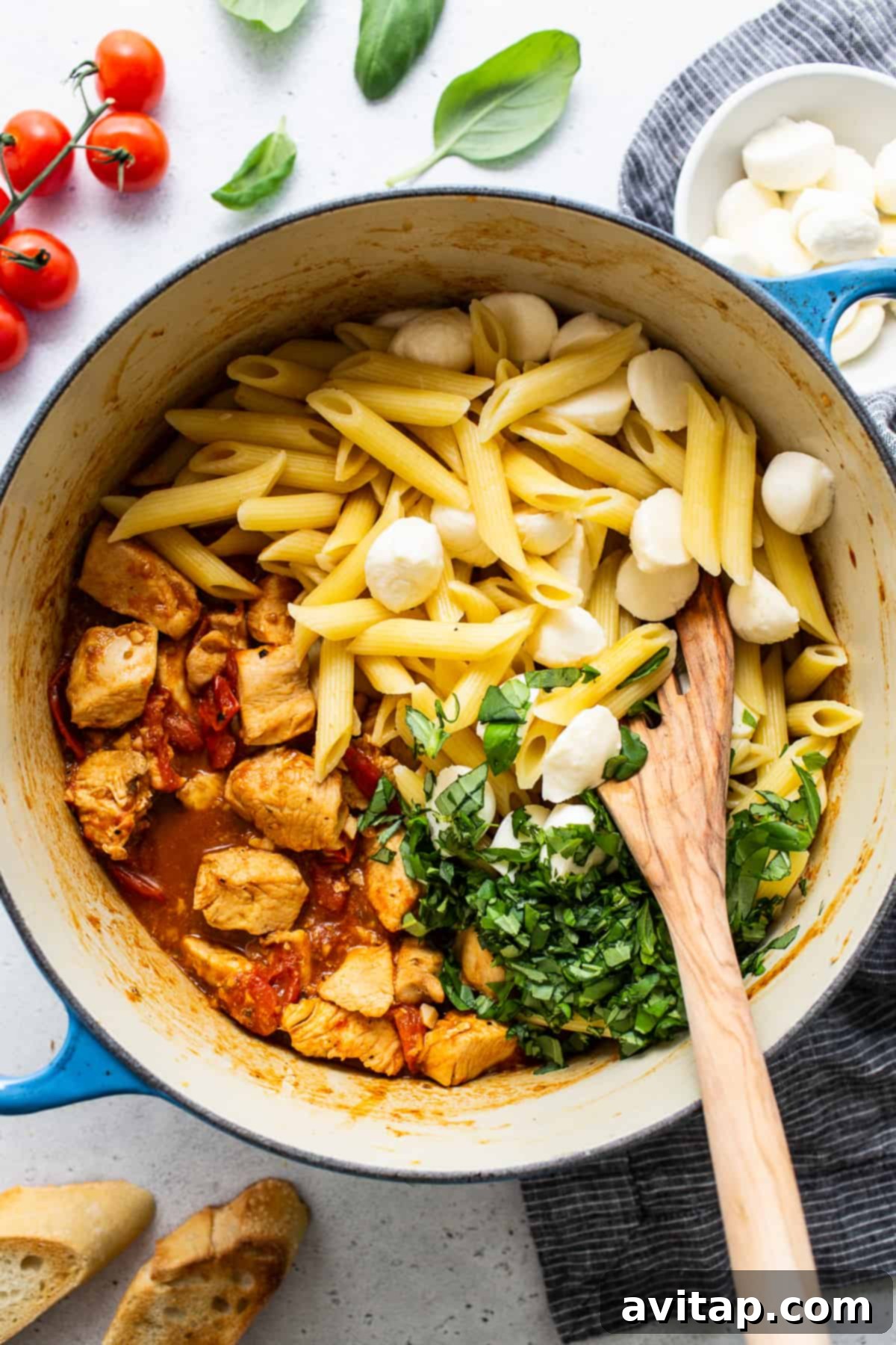 Chicken Caprese pasta simmering in a large pot, with vibrant tomatoes and fresh basil notes.