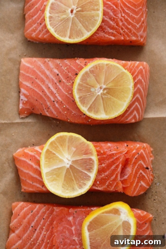 Broiled Salmon Fillets with Lemon Four salmon fillets topped with lemon wedges ready for broiling