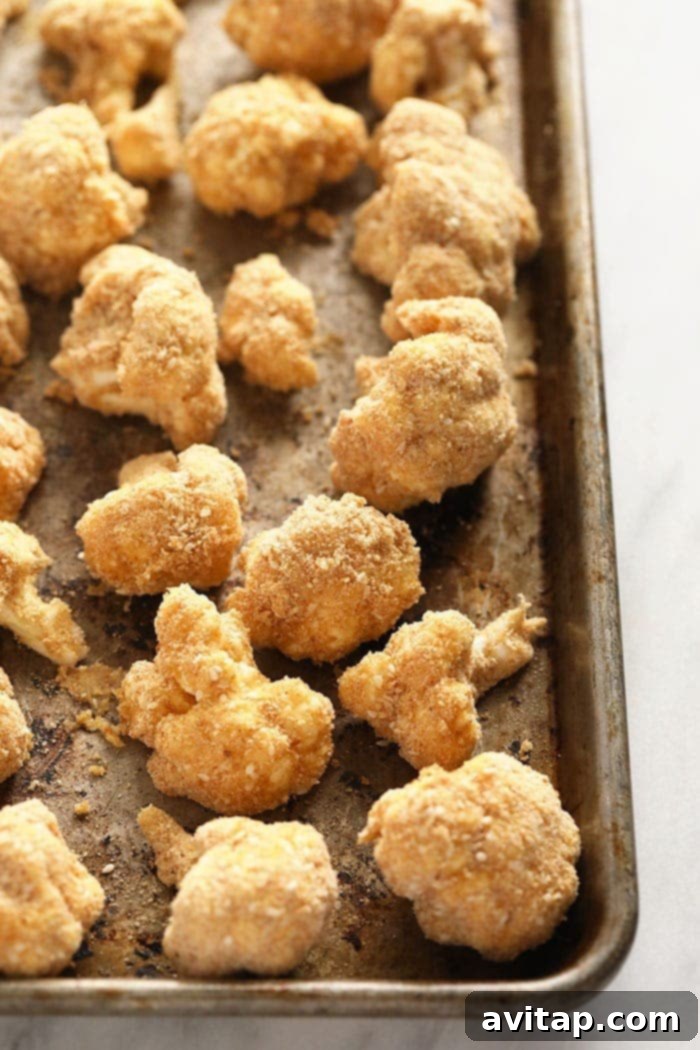 Crispy cauliflower florets baked to golden perfection for General Tso's Breaded cauliflower florets arranged on a baking sheet, ready to be baked into crispy wings