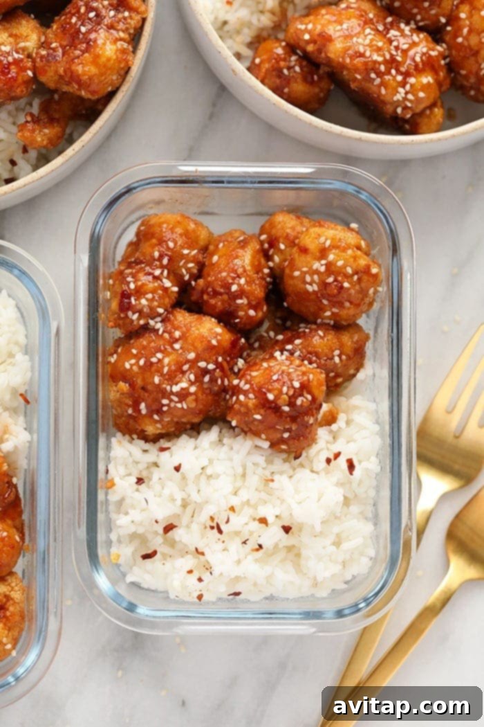 General Tso's Cauliflower served with white sticky rice in a prepared meal prep container, garnished with sesame seeds.