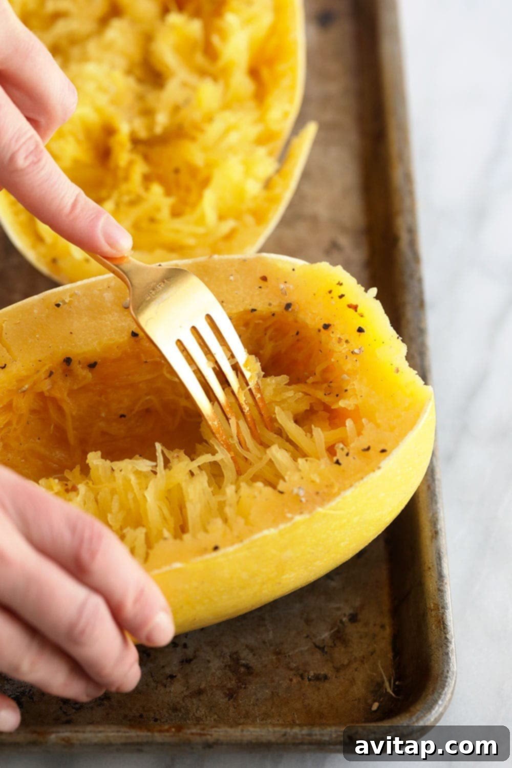 Gently shredding cooked spaghetti squash into noodle-like strands with two forks