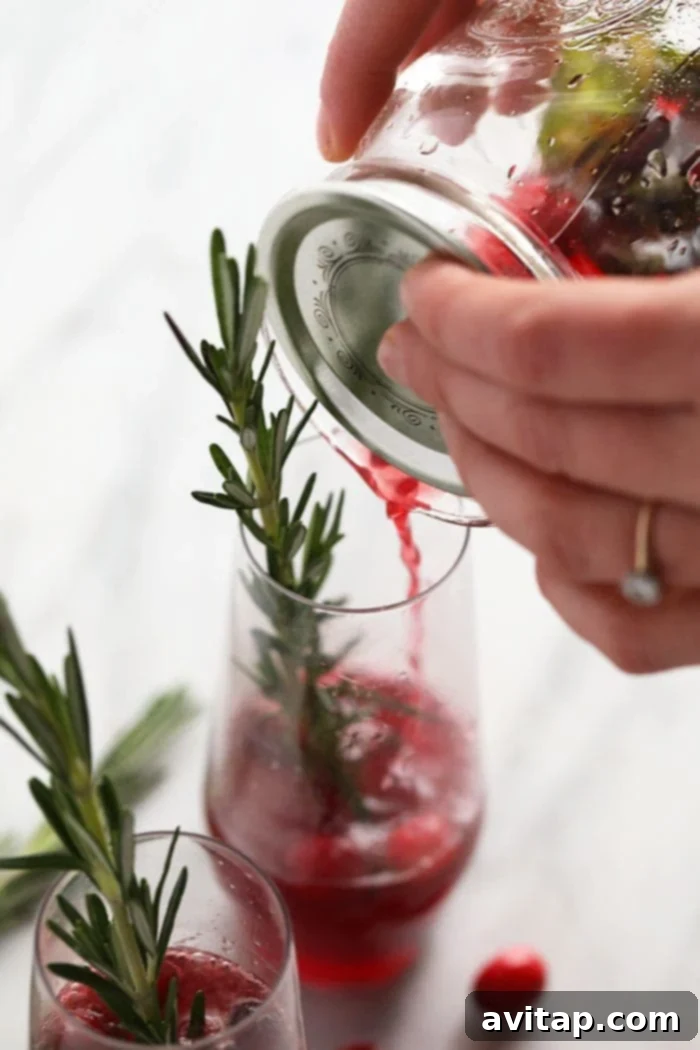 Pouring the freshly shaken Cranberry Mojito into a glass filled with ice, ready for sparkling water and garnish.