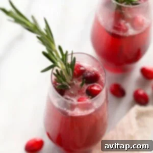 Two glasses with cranberries and rosemary sprigs.