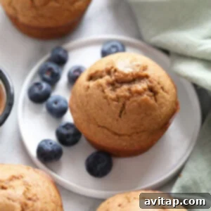 A plate with golden almond butter banana bread muffins and fresh blueberries.