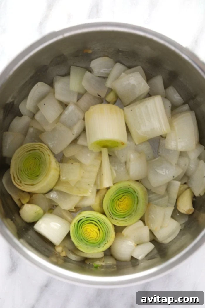 onions, leeks and garlic cloves being sautéed in the instant pot