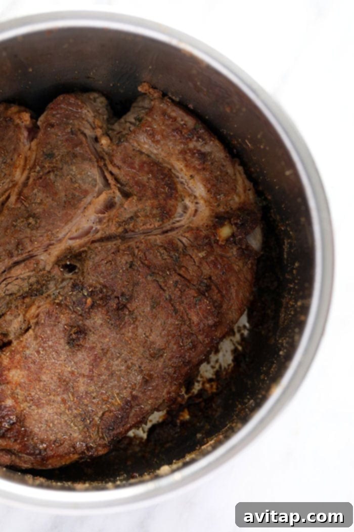 Chuck roast being seared to a golden brown in the Instant Pot before pressure cooking