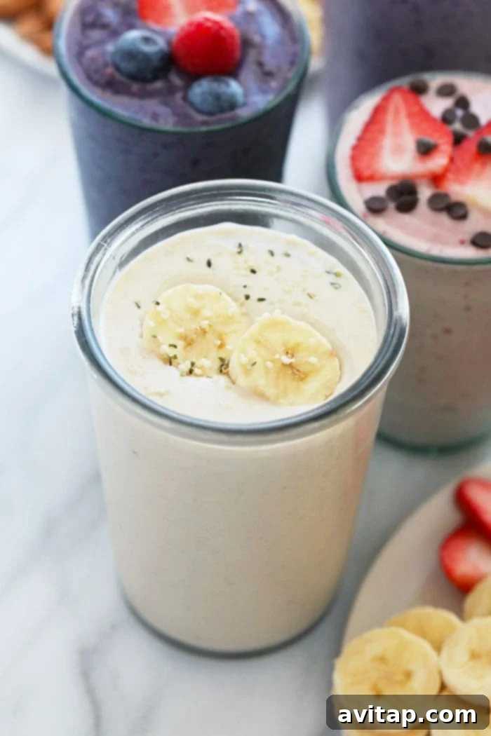 A creamy banana protein shake in a glass, topped with sliced bananas and a sprinkle of cinnamon, against a light background.