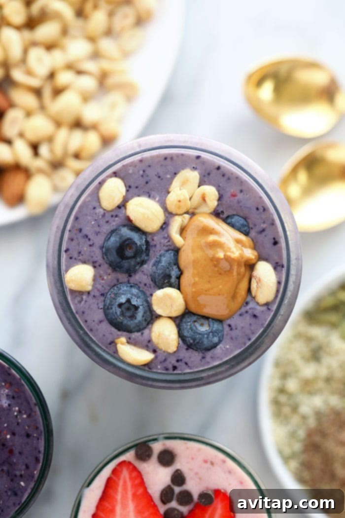 A layered PB&J protein shake in a glass, showing distinct peanut butter and berry layers, evoking a nostalgic favorite.