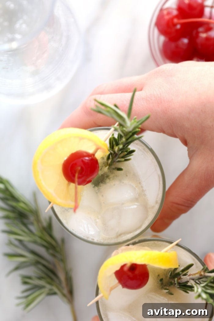 Rosemary Collins cocktail in a tall glass, beautifully garnished with a sprig of fresh rosemary and a lemon slice, on a white surface.
