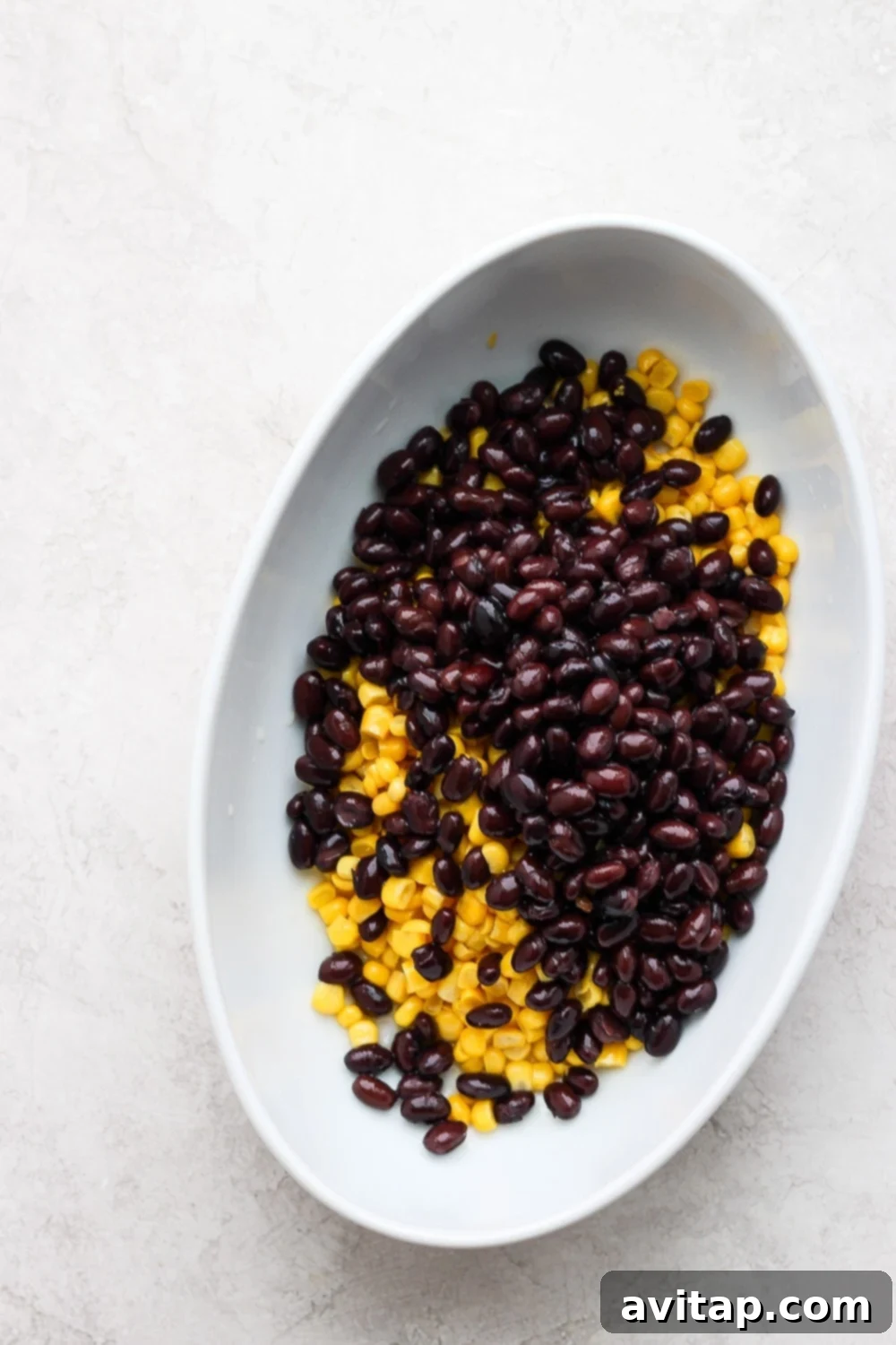 sweet corn kernels and black beans in separate bowls, ready to be mixed into the vegan queso base