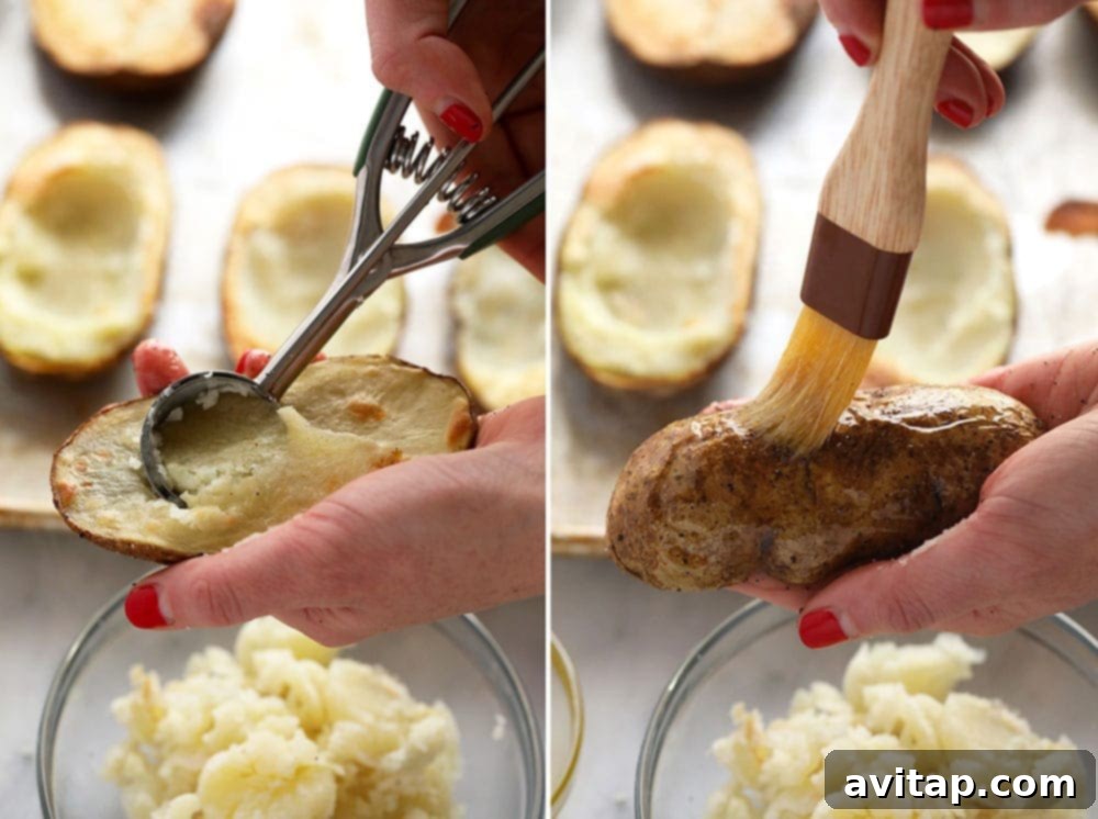 A close-up shot of a hand using a cookie scoop to carefully remove the fluffy potato flesh from a baked potato half, preparing it for filling.