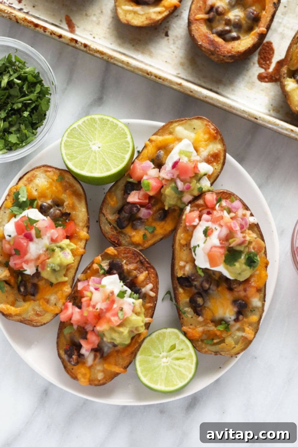 A vibrant platter of healthy vegetarian Mexican potato skins, topped with guacamole, Greek yogurt, and fresh cilantro, ready to be enjoyed.