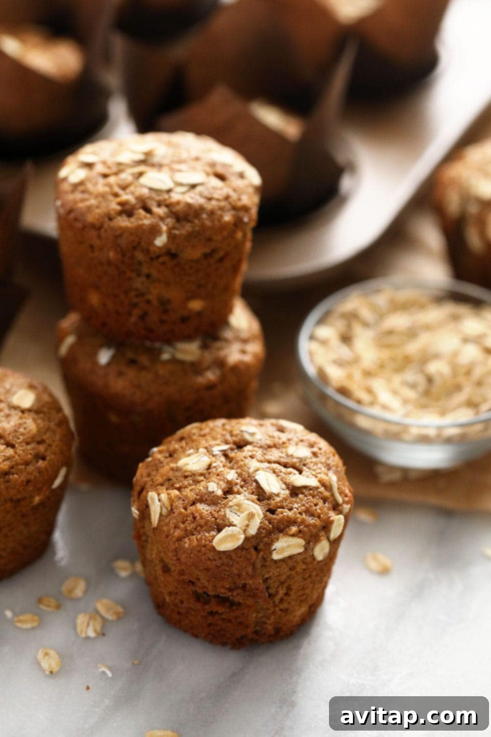 Hearty Oatmeal Muffins 6 A stack of three classic oatmeal muffins on a wooden surface, showcasing their delicious texture.