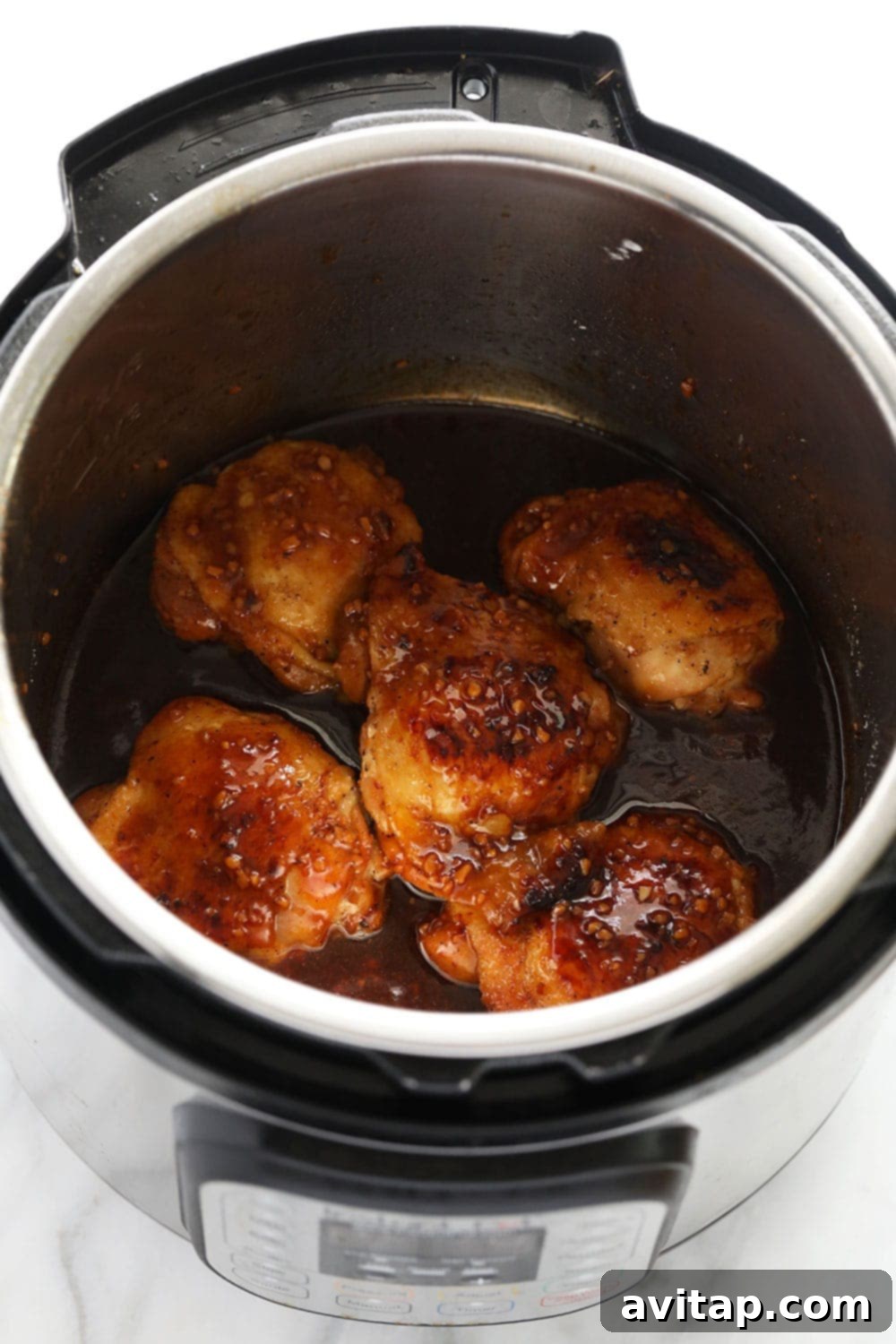 Honey garlic chicken thighs cooking in the Instant Pot, glistening with sauce.