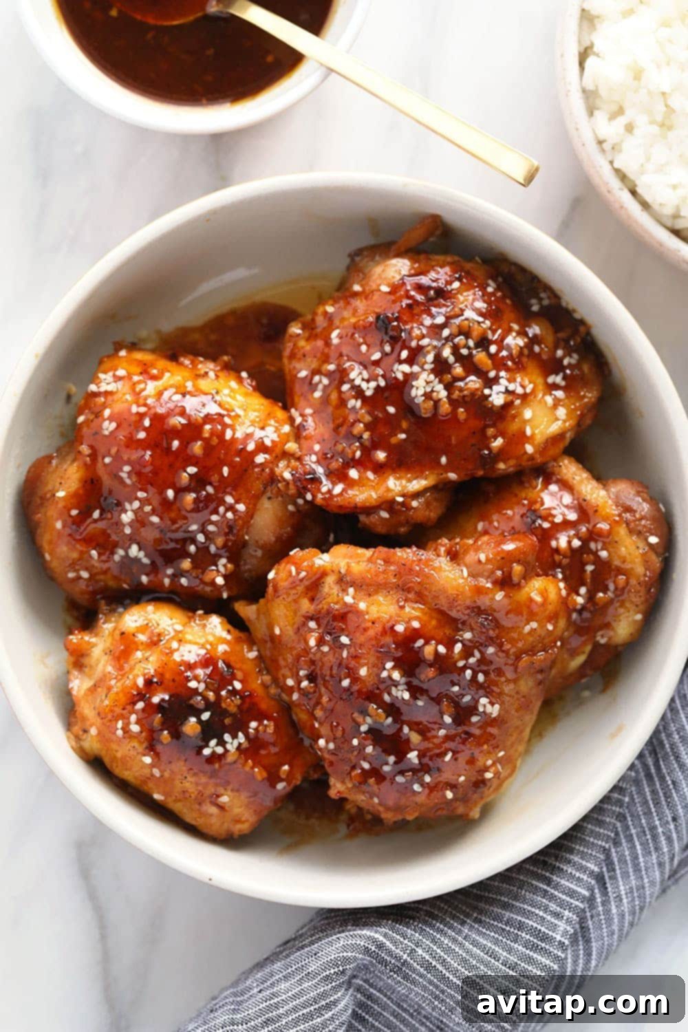 Close-up of honey garlic chicken thighs in a bowl, garnished with sesame seeds.