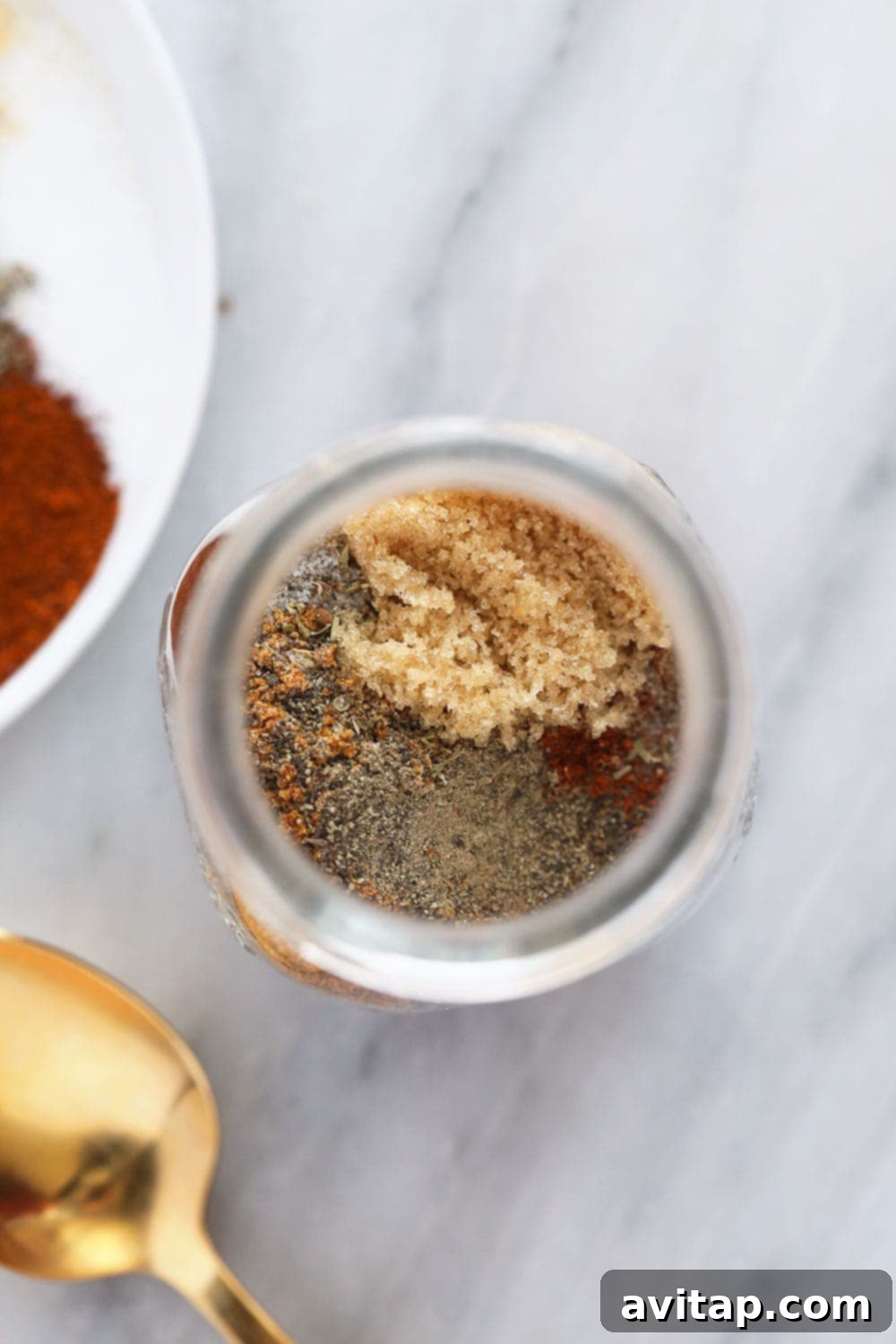 Homemade Cajun Seasoning stored neatly in a clear glass jar on a wooden surface.