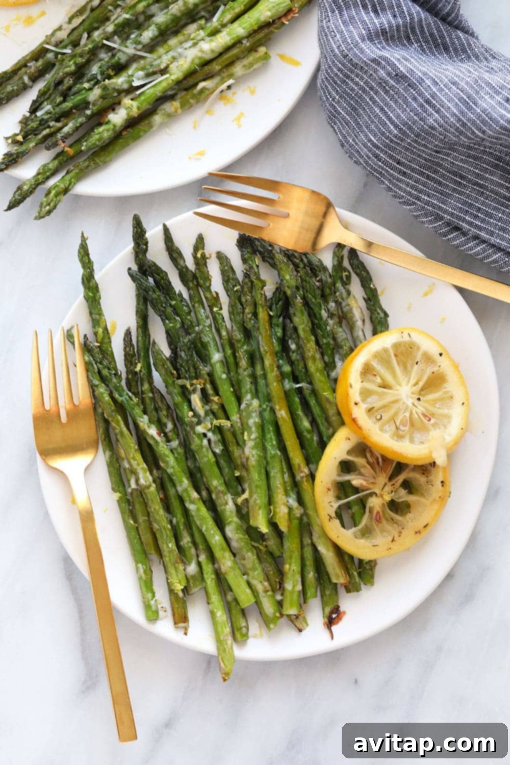 Freshly oven-roasted asparagus with lemon zest garnish on a white plate. 
