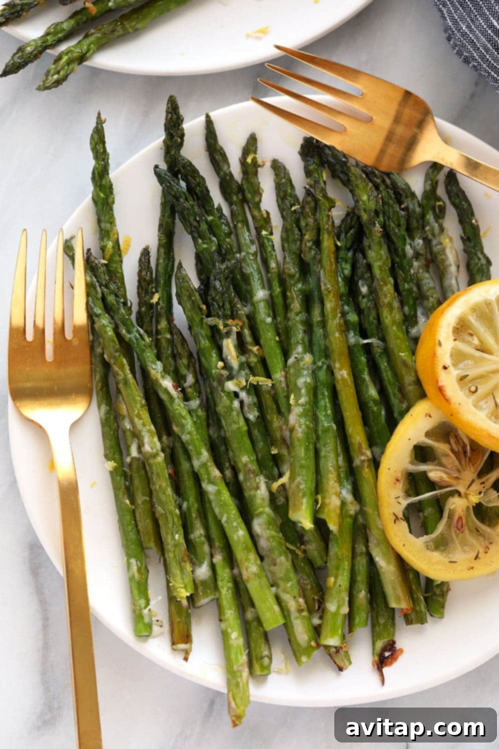 Oven roasted asparagus with parmesan cheese and lemon zest on a white plate, ready to be served.