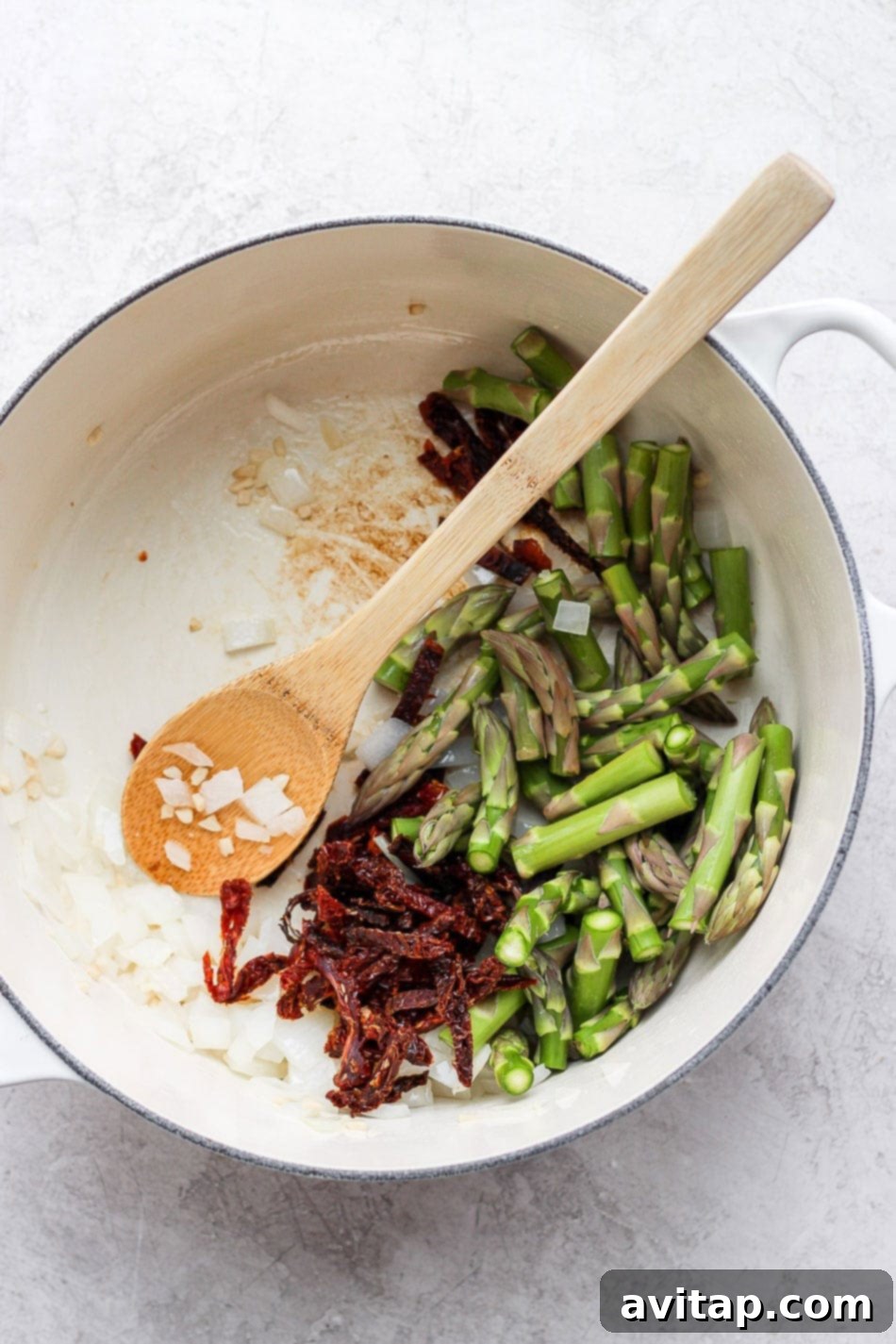 Velvety Vegan Asparagus Pasta 4 asparagus, sun-dried tomatoes and onions in a dutch oven ready to be sauteed