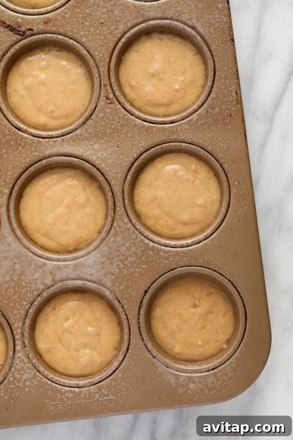 Muffin Batter in Tin Muffin batter neatly scooped into a muffin tin, ready for baking.