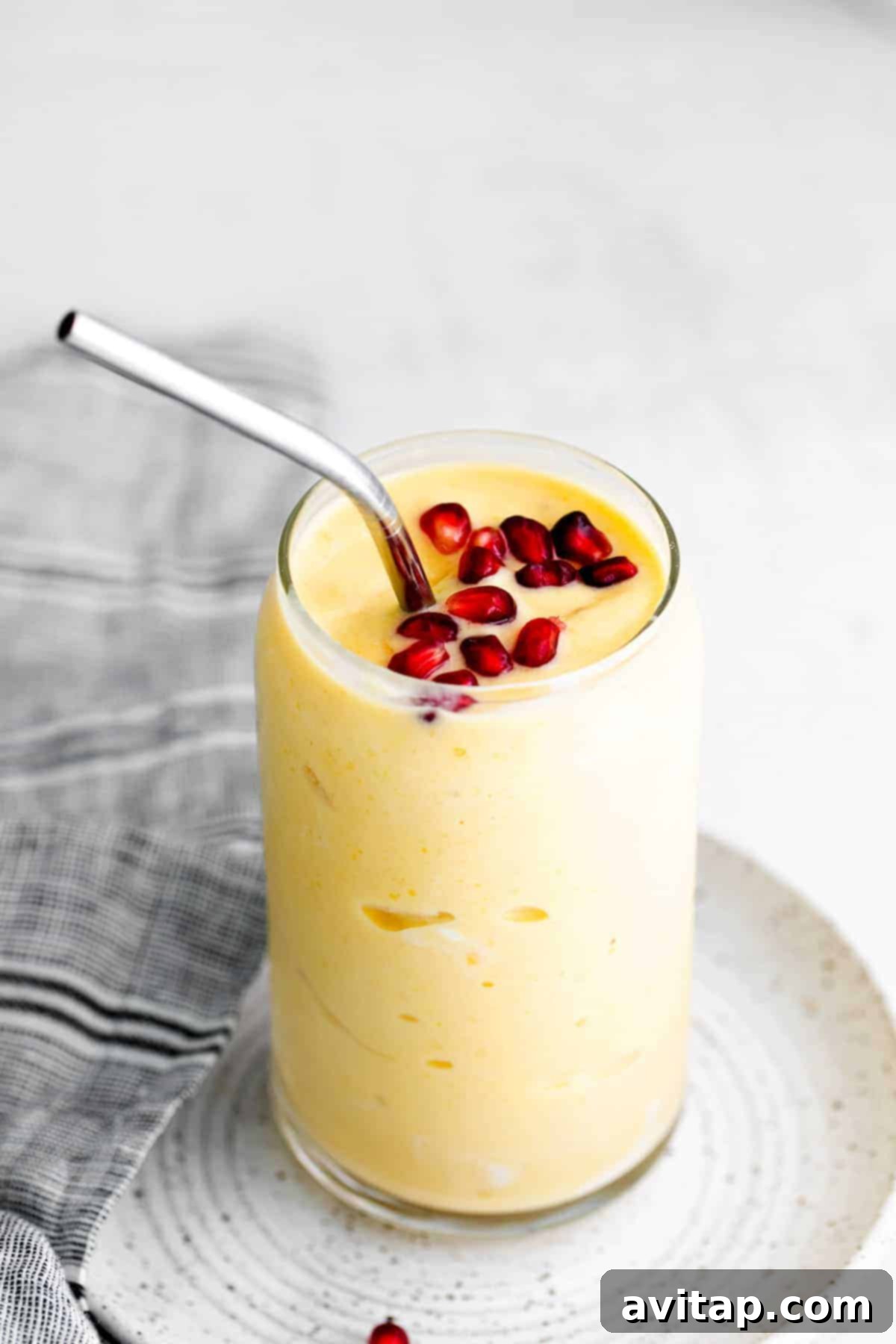 A vibrant, creamy mango smoothie served in a clear glass, garnished beautifully for a tropical feel.