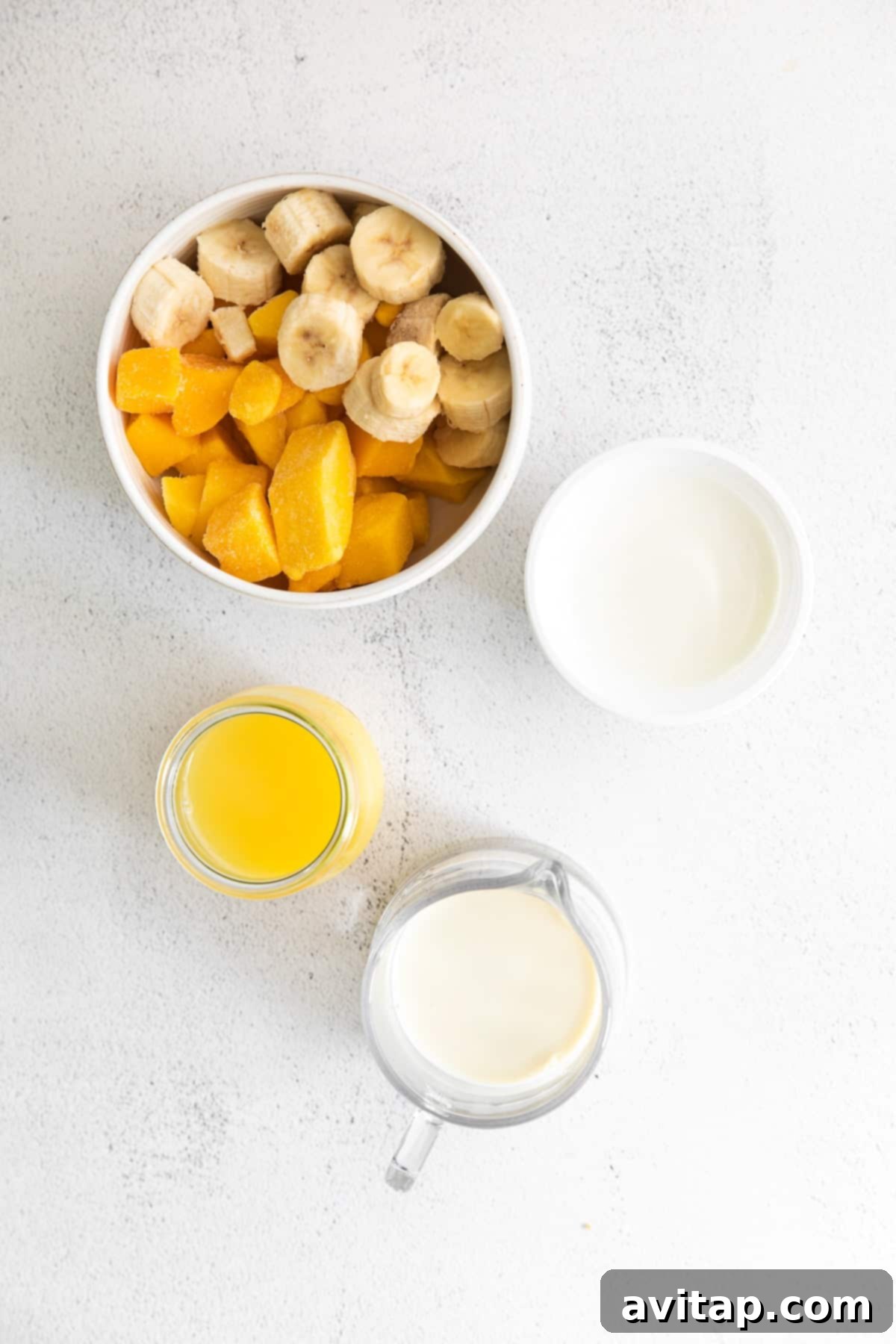 A selection of fresh and frozen ingredients including frozen mango chunks and a frozen banana, ready to be blended into a smoothie.