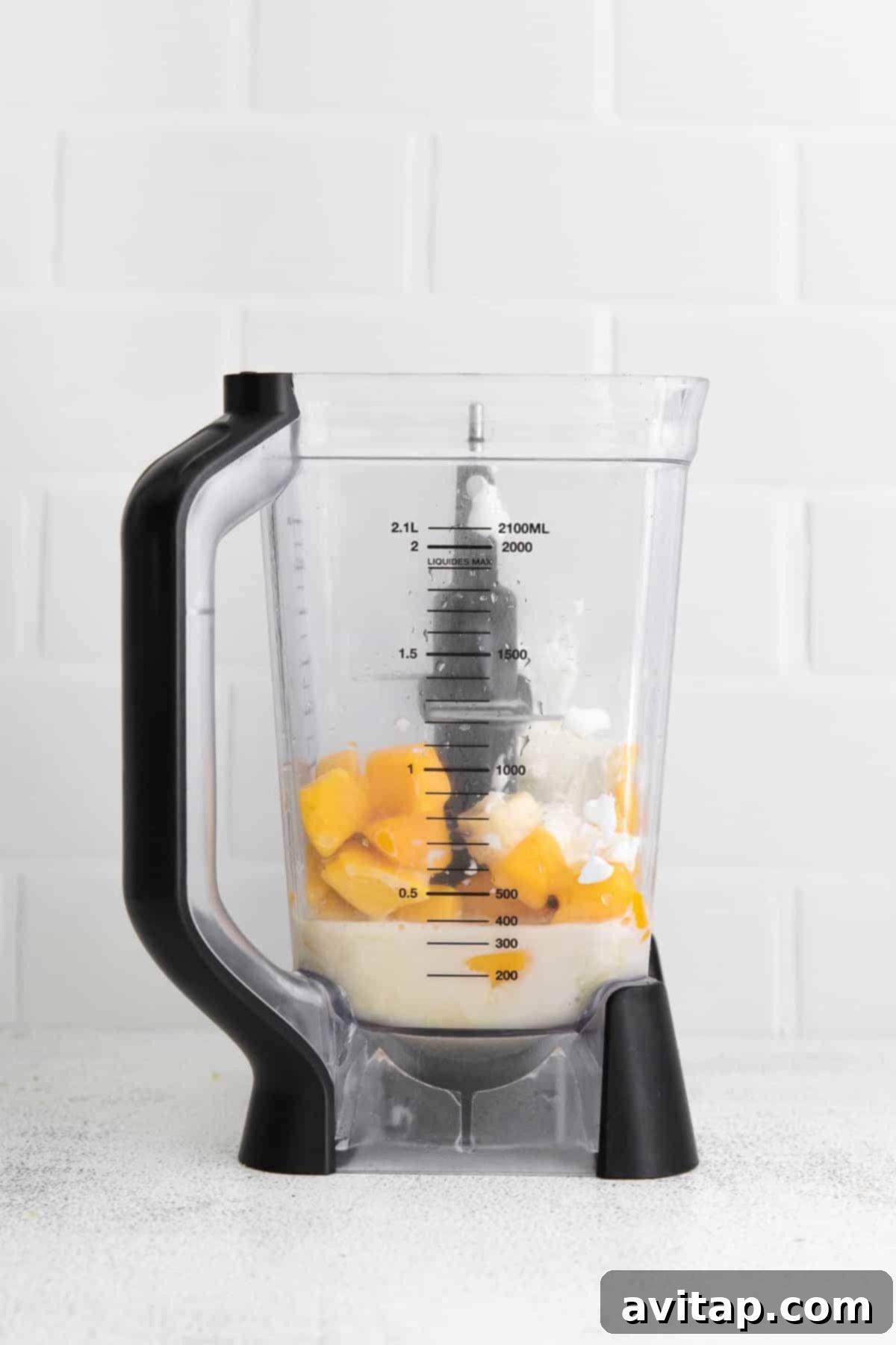 All ingredients for the mango smoothie are being blended together in a high-speed blender, creating a smooth, creamy texture.