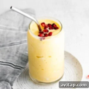 A beautifully presented mango smoothie in a glass with pomegranate seeds, ready to be enjoyed.
