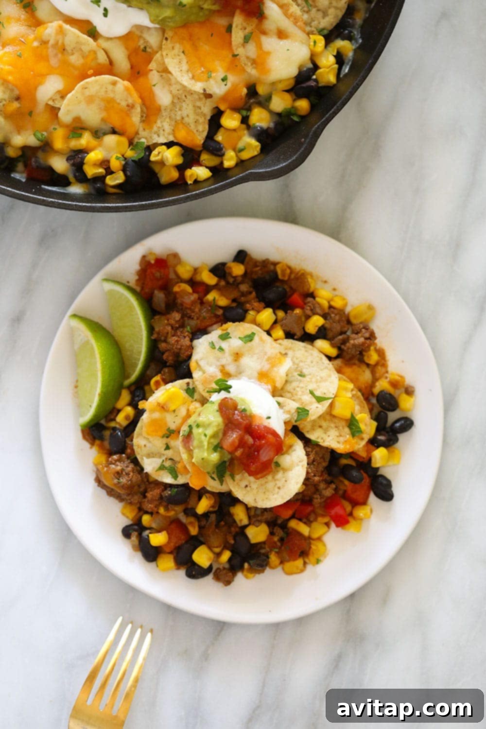 Easy taco casserole on a plate topped with creamy Greek yogurt and fresh guacamole