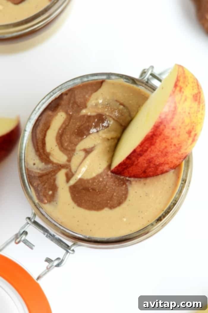 Crisp apple slices generously dipped in creamy Chocolate Vanilla Swirl Cashew Butter, a perfect healthy snack.