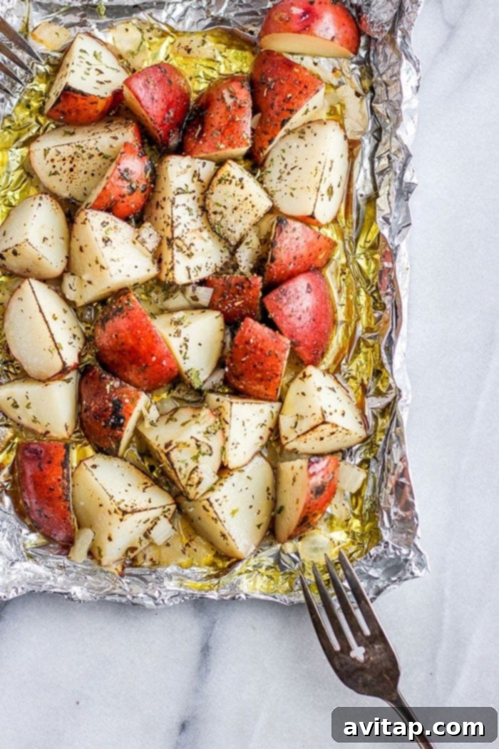 Red potatoes on tin foil covered in olive oil and spices, ready for grilling