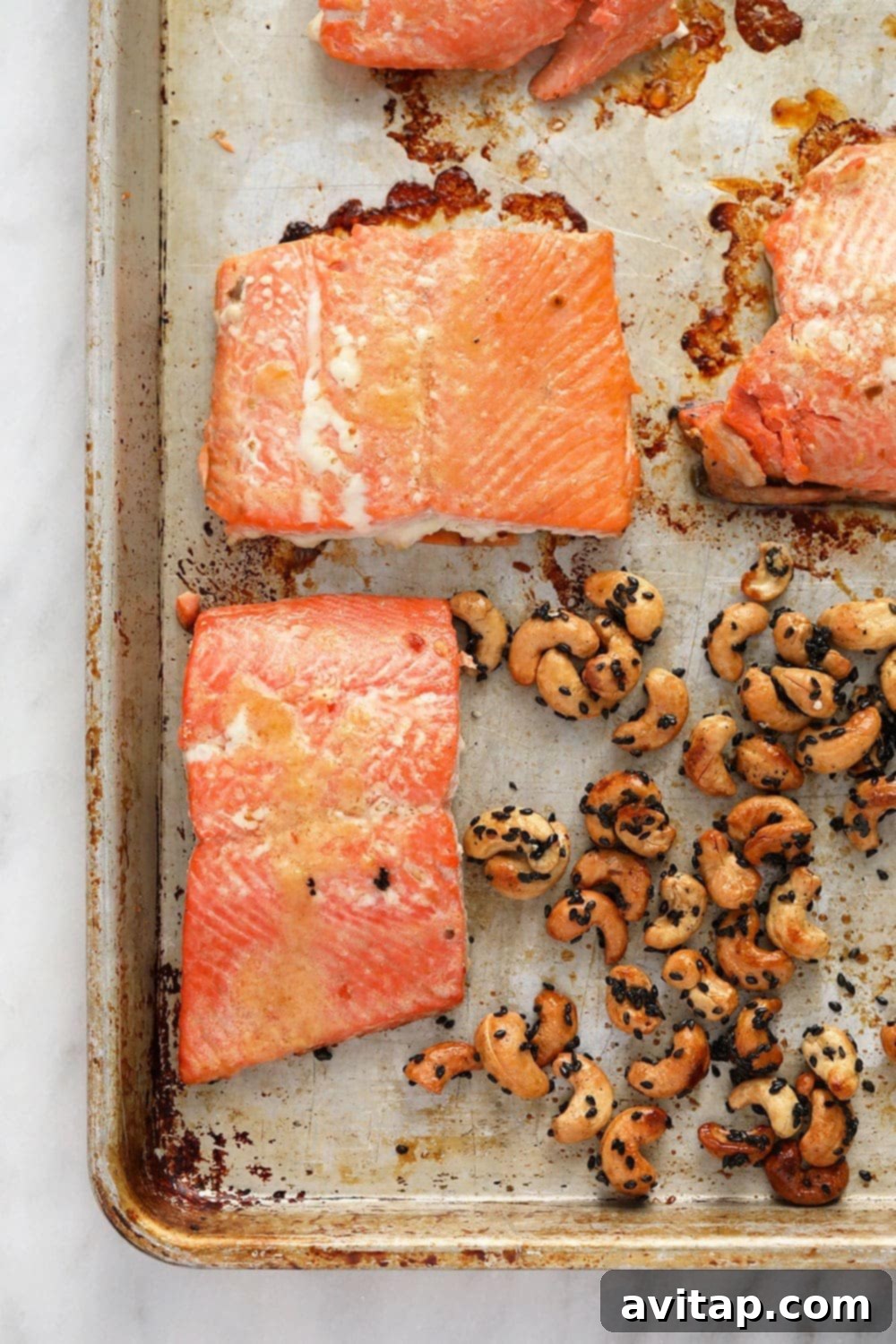 Salmon and maple sesame cashews arranged on a single baking sheet