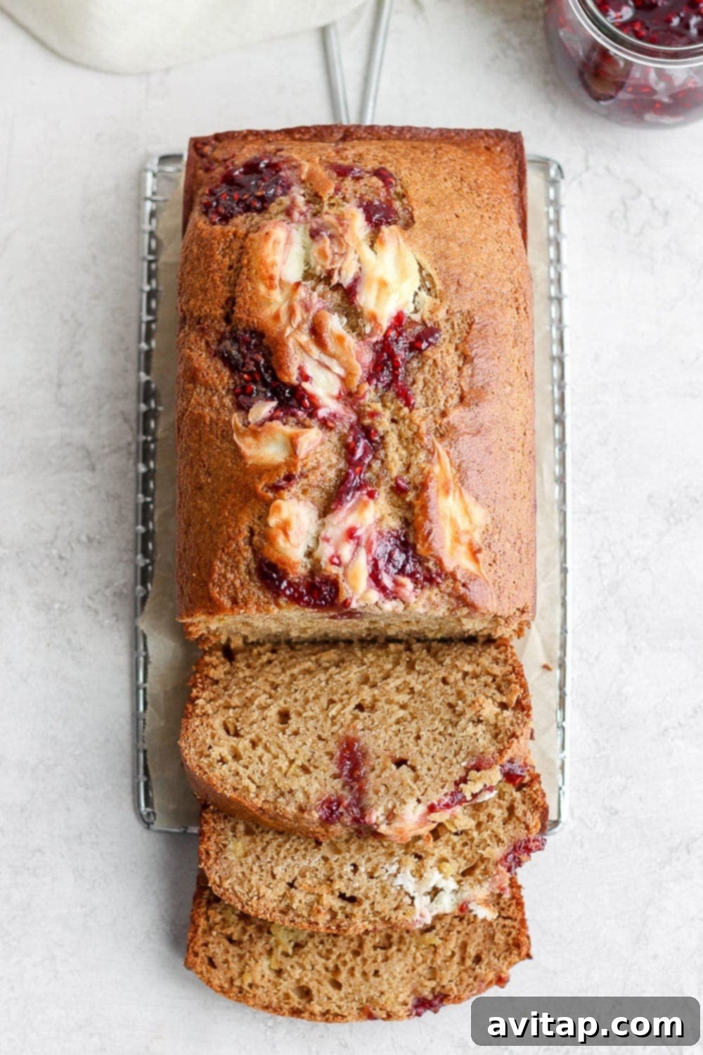 Sliced lemon bread revealing a beautiful raspberry and cream cheese swirl, resting on a white surface.