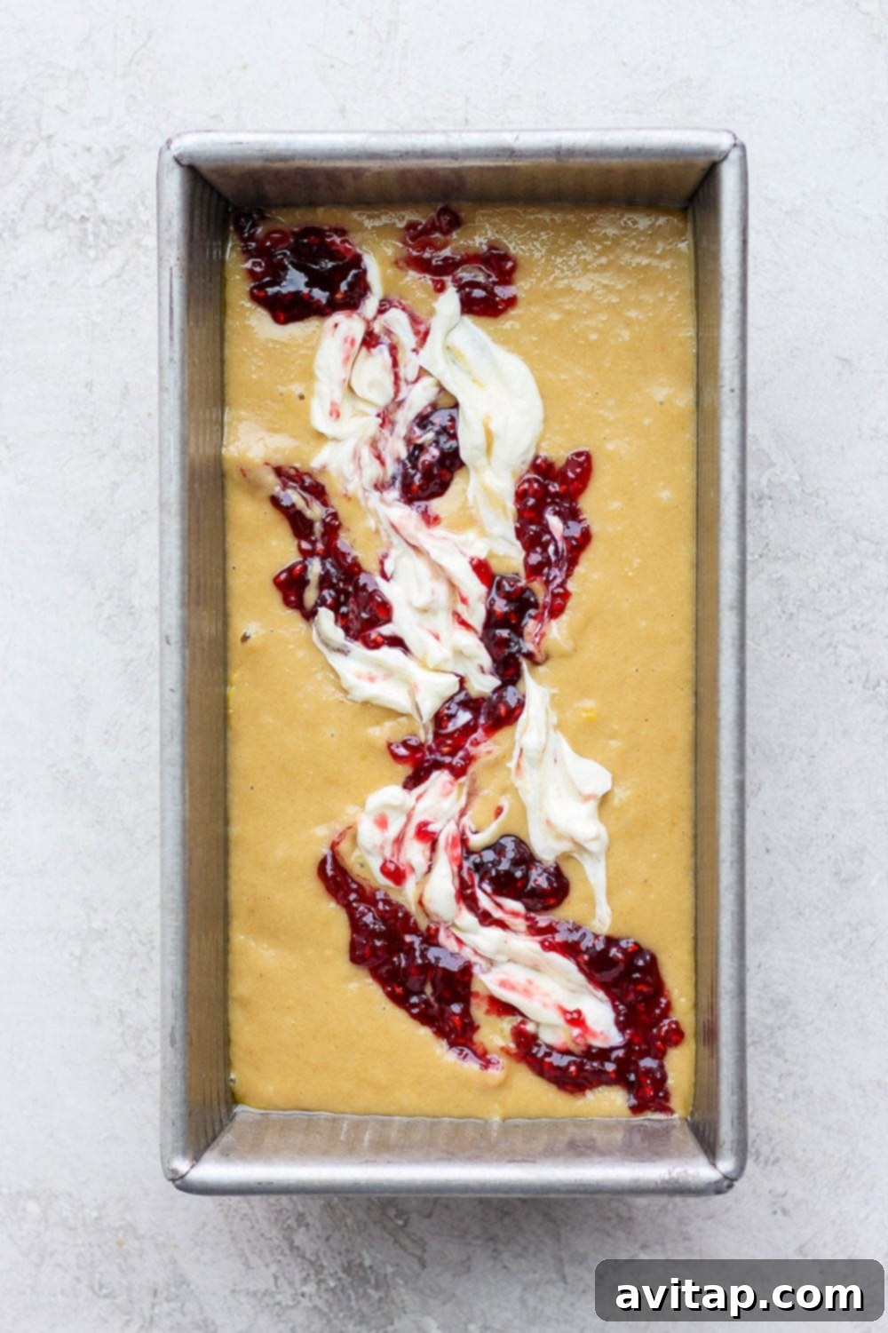 Lemon bread batter evenly spread in a loaf pan, ready for the swirl topping and baking.