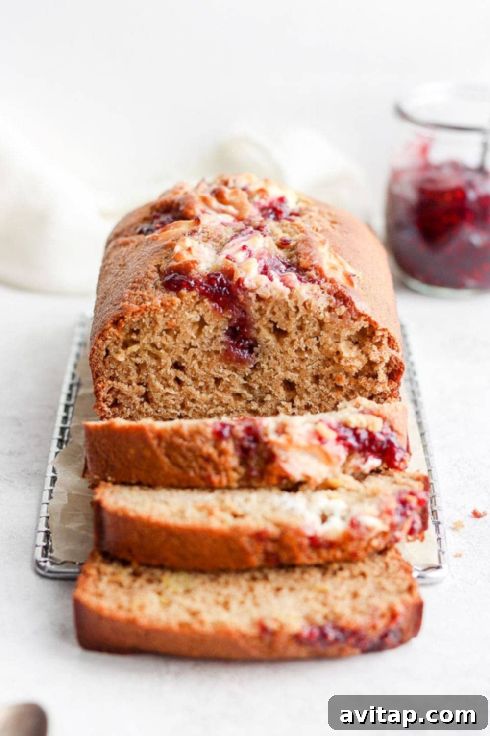 Multiple slices of lemon bread with raspberry cream cheese swirl arranged on a wooden board.