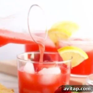 Boozy Strawberry Lemonade 5 A glass of strawberry lemonade infused with a splash of strawberry vodka being poured into a glass, ready to be enjoyed.