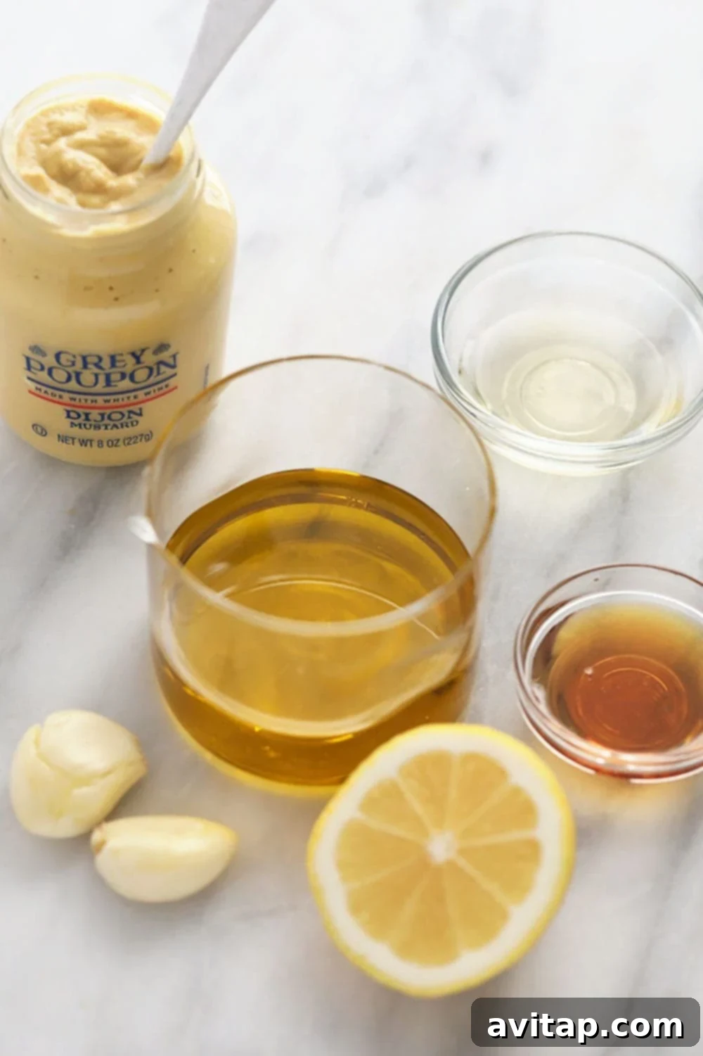 Collection of fresh ingredients for homemade lemon vinaigrette dressing, including lemons, olive oil, white wine vinegar, dijon mustard, maple syrup, and garlic.