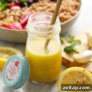 Homemade lemon vinaigrette dressing in a clear glass jar, with fresh lemons visible in the background, highlighting the key ingredient.