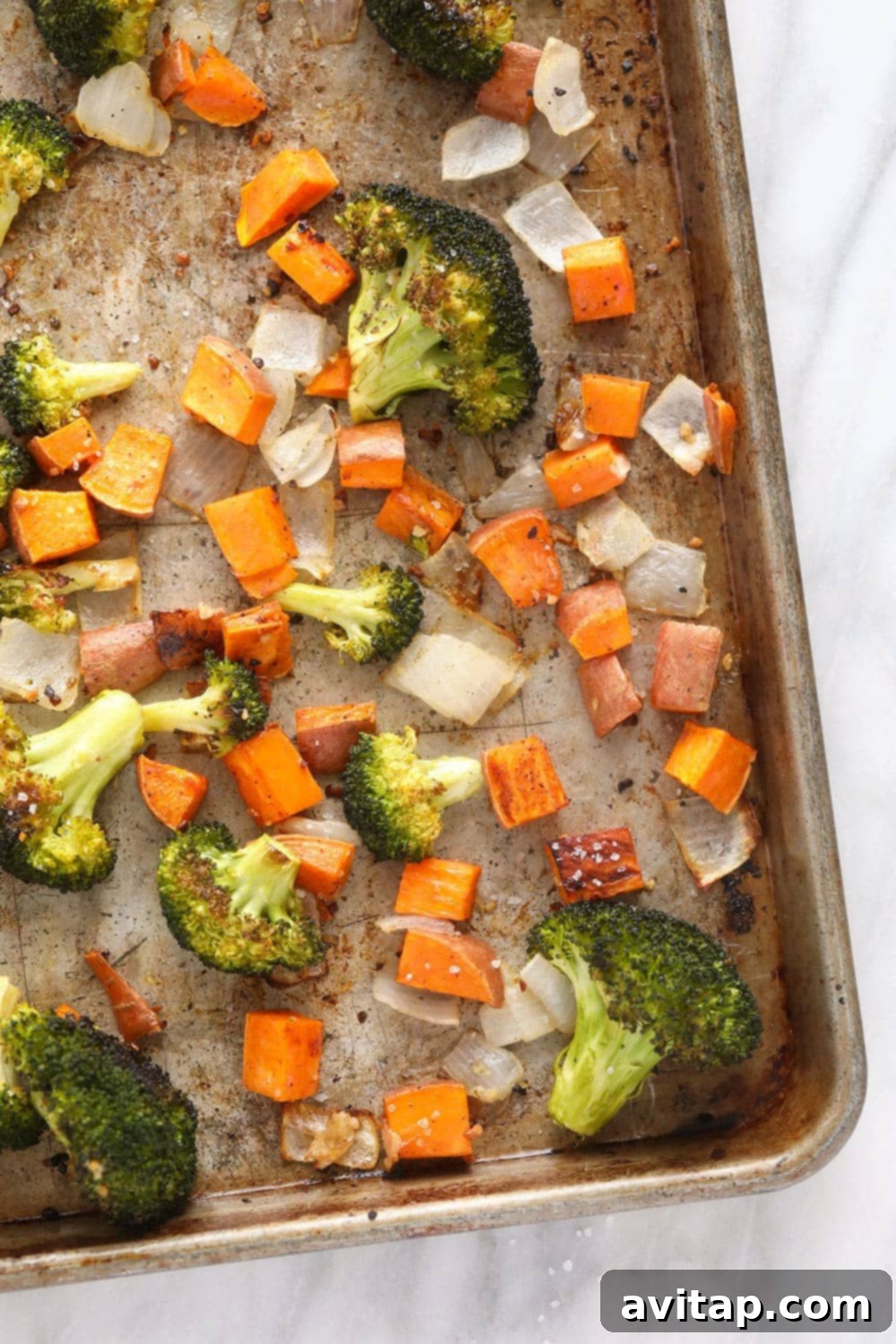 Assorted roasted vegetables, including sweet potato, onion, and broccoli, prepared for the vegetarian brown rice bowl