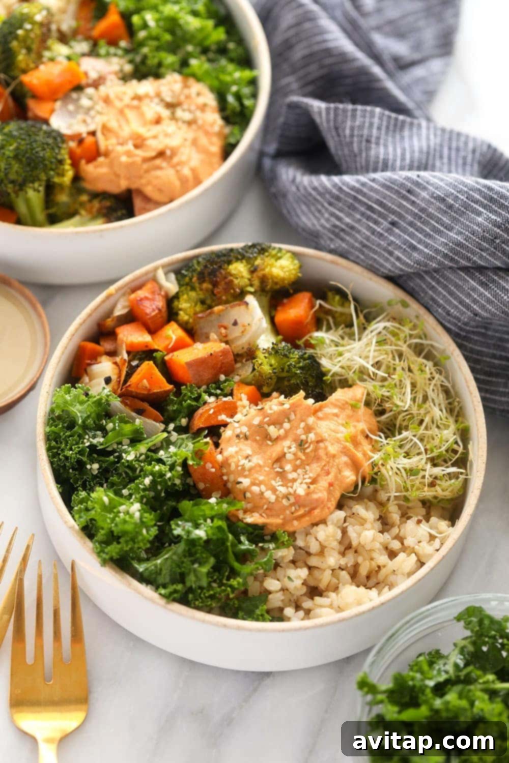 A beautifully arranged vegetarian brown rice bowl, showcasing layers of roasted vegetables, brown rice, fresh greens, and hummus, ready to be enjoyed