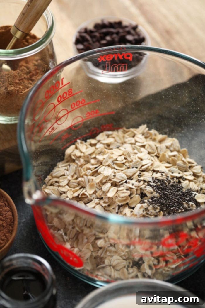 Close-up of dry rolled oats and chia seeds being mixed in a bowl, illustrating the first step of preparation