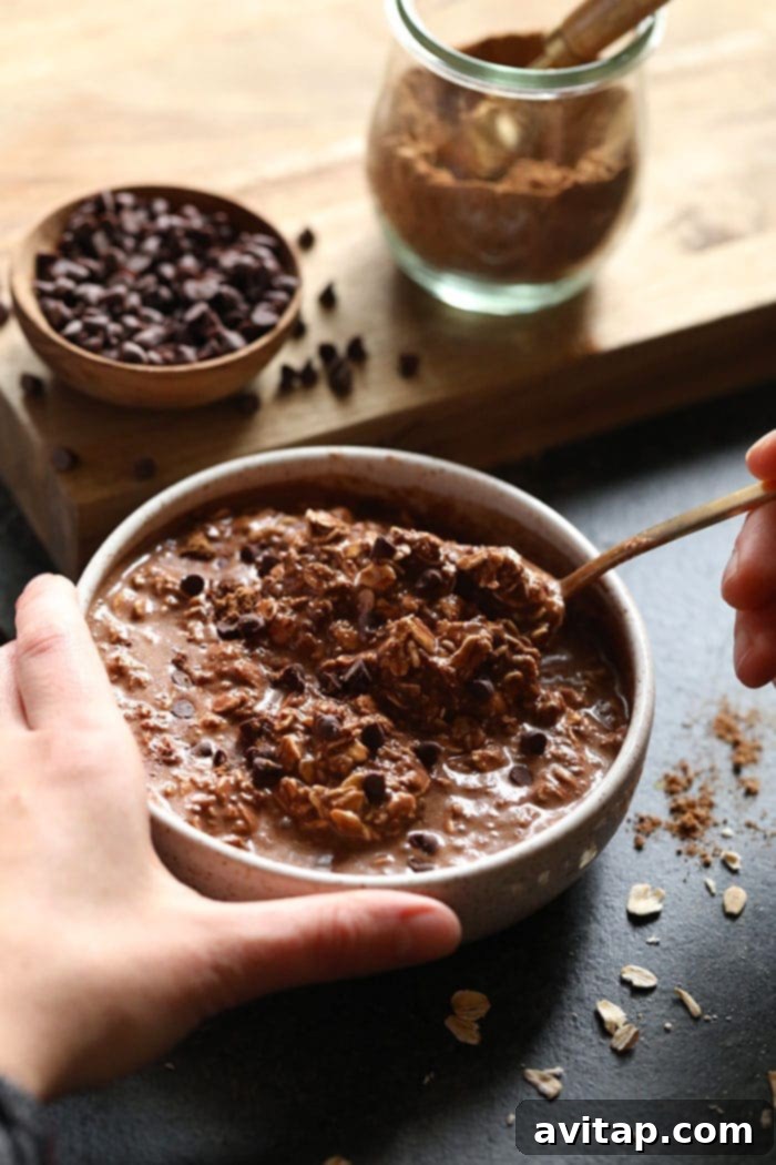 A beautifully presented bowl of chocolate chai vegan overnight oats, ready to be enjoyed, with a spoon in it