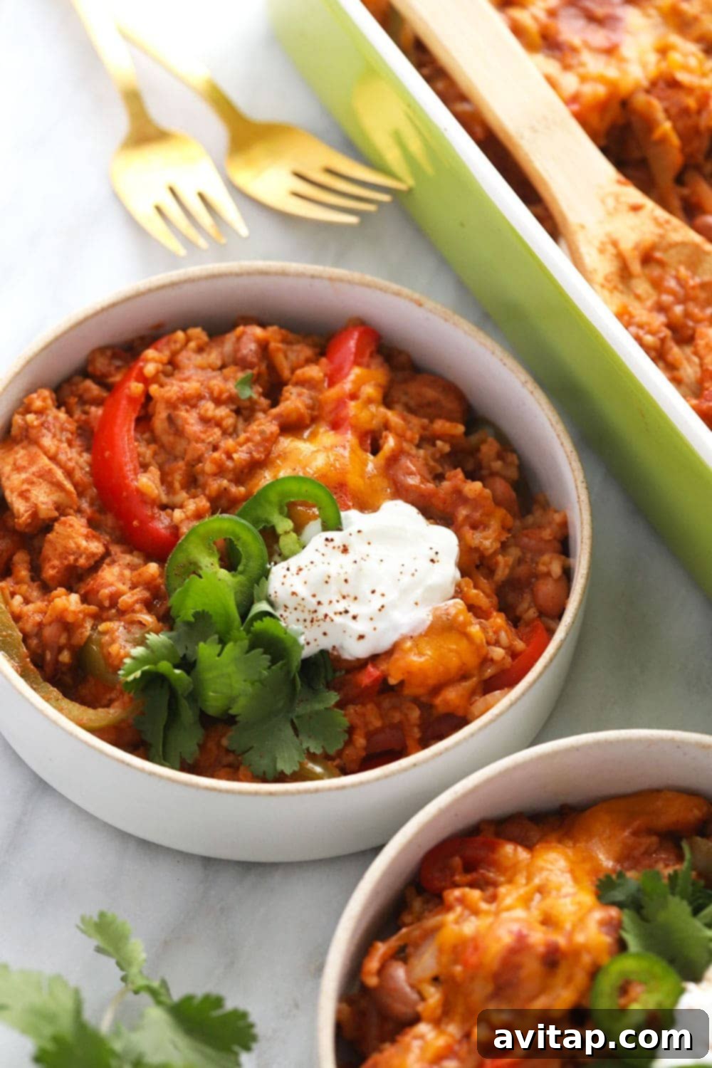 Healthy Chicken Burrito Bowl Casserole in a bowl, topped with sliced jalapeños and Greek yogurt