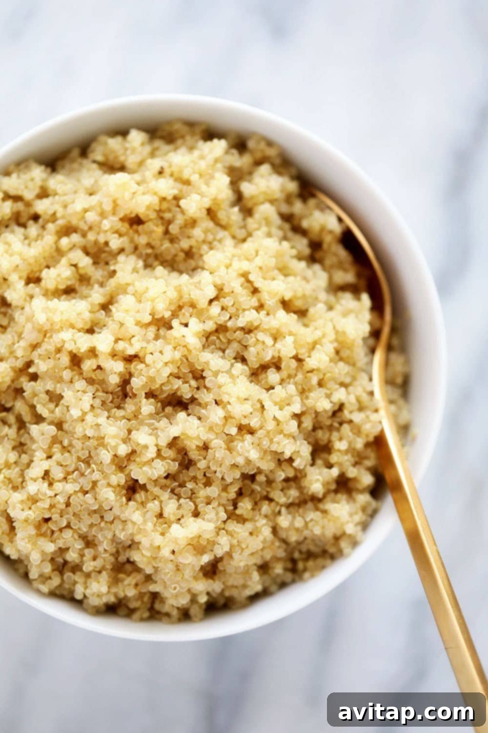 Looking for a foolproof method in how to cook quinoa? In this post, we'll teach you all about the superfood called quinoa, the different ways to make it, and how to incorporate it into your meals! A serving of fluffy, perfectly cooked quinoa in a white bowl, garnished and ready to be enjoyed.