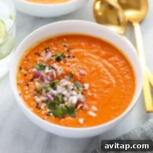A bowl of Instant Pot sweet potato carrot ginger soup, topped with fresh herbs.